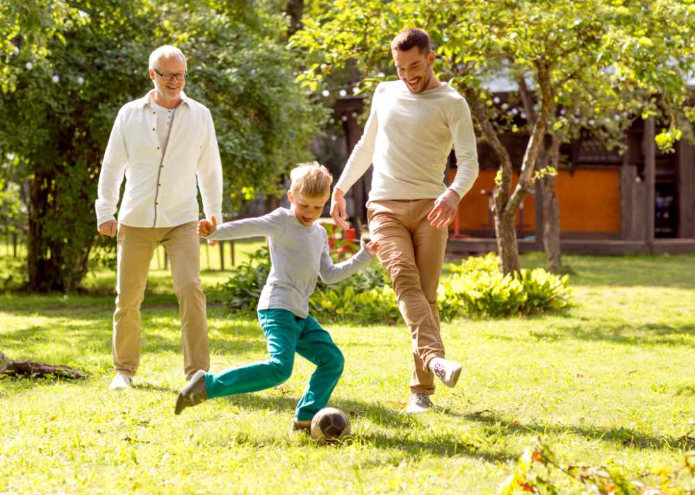 drei generationen spielen gemeinsam Fußball im Garten
